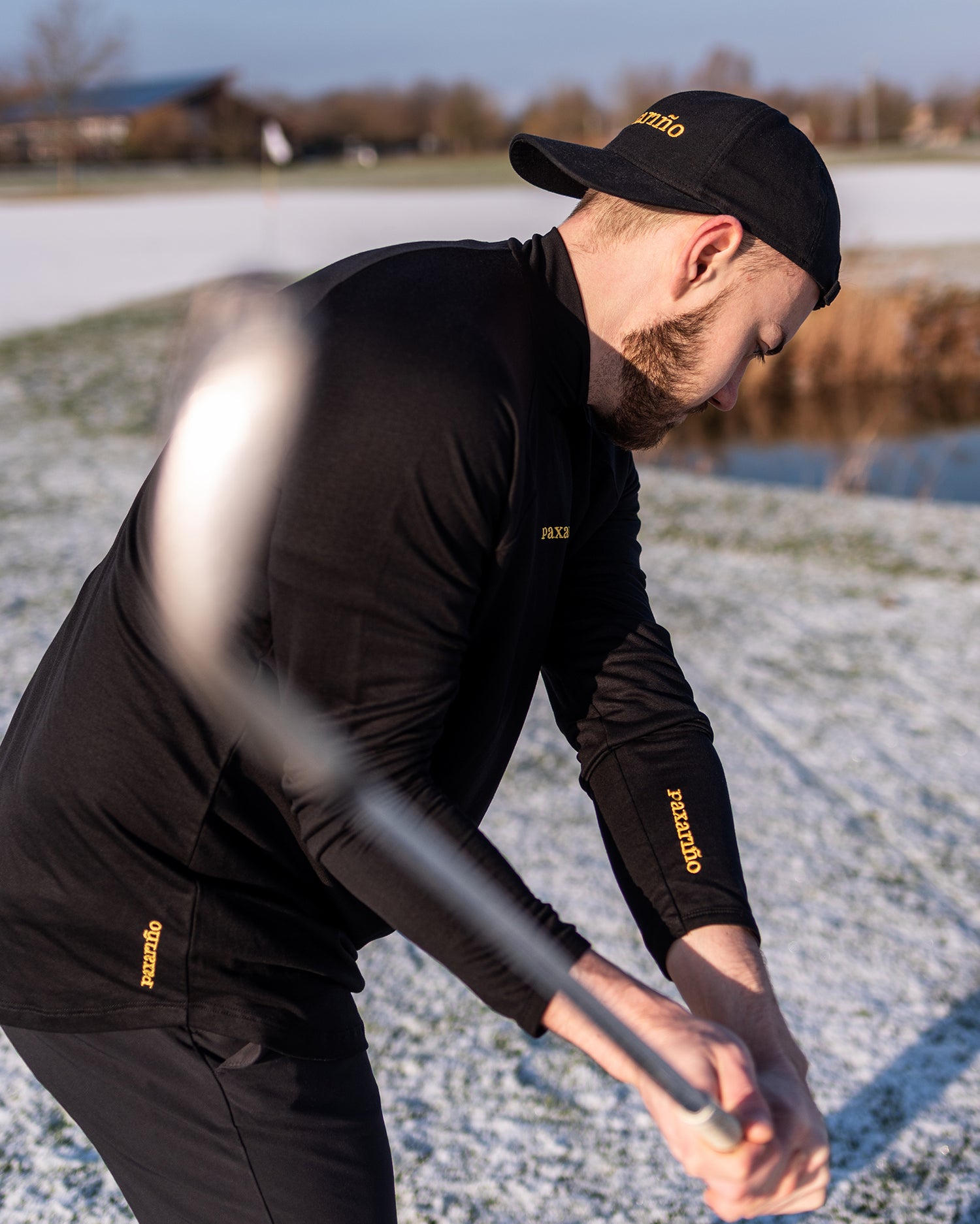 Co-Founder Sebastian take a swing on a snowy golfcours, while staying warm wearing the TENCEL™ Longsleeve by paxariño.